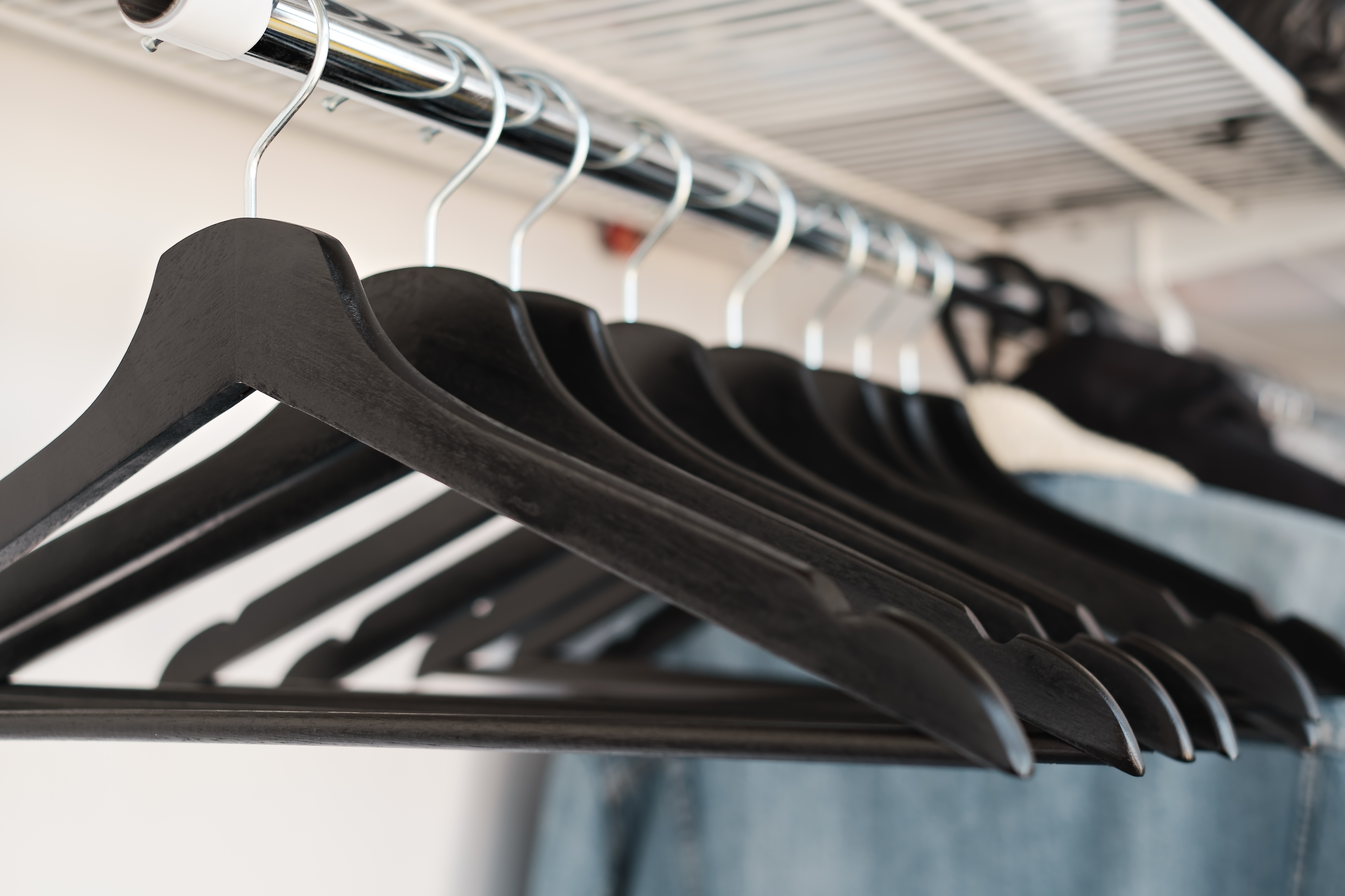 Schwarze Holzkleiderbügel auf einer Kleiderstange